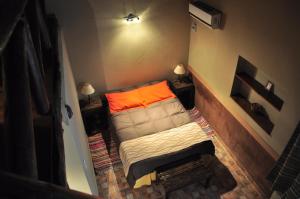 a small room with a couch with an orange pillow at Casagrande Hotel de Adobe in Tinogasta