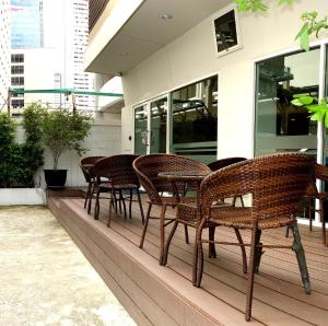 een rij rieten stoelen en tafels op een veranda bij Nantra Silom in Bangkok