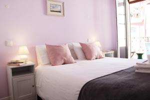 a bedroom with a large white bed with pink pillows at Quebra Luz in Coimbra