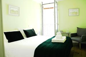 a bedroom with a large white bed with a chair at Quebra Luz in Coimbra