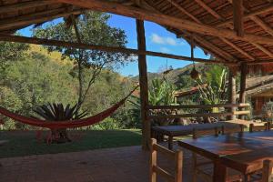 eine Terrasse mit einer Hängematte sowie einem Tisch und Stühlen in der Unterkunft Pousada Dona Felicidade in Cunha
