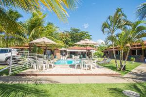 una piscina con mesas, sillas y sombrillas en Pousada Casuarina Geribá, en Búzios