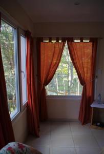 a room with two windows with red curtains at Familia Piatti B&B - Suites in Ushuaia