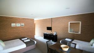 ein Hotelzimmer mit 2 Betten, einem Tisch und einem Schreibtisch in der Unterkunft Ashleigh Court Motor Inn in Mulwala
