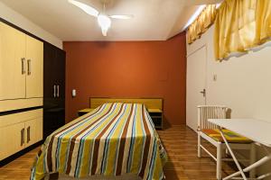 a room with a bed with a striped sheet on it at Hotel Econômico ao lado do Metrô in São Paulo