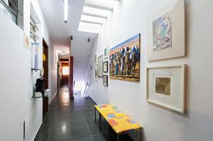 a hallway with a bench and paintings on the wall at Hotel Econômico ao lado do Metrô in São Paulo
