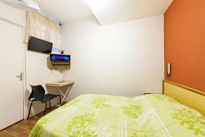 a bedroom with a bed and a desk and a television at Hotel Econômico ao lado do Metrô in São Paulo