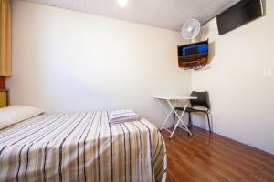 a bedroom with a bed and a desk and a tv at Hotel Econômico ao lado do Metrô in São Paulo
