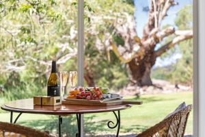 a table with a bottle of wine and a plate of fruit at Adelaide Hills Retreats in Balhannah