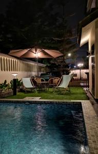 ein Pool mit Stühlen und Sonnenschirmen in der Nacht in der Unterkunft RIA Homestay in Johor Bahru