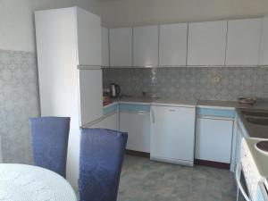a small kitchen with white cabinets and blue chairs at APARTMENT PRIMČEVA in Maribor