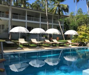 a swimming pool with umbrellas and chairs at Plantation House in Hikkaduwa