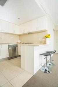 a white kitchen with a counter and a stool at Designed Home of Ultimate Convenience In Gordon in Pymble