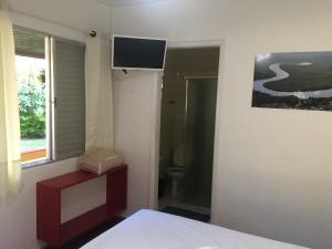 a bedroom with a bed and a television on the wall at Pousada Poleto's in Bertioga