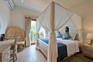 a bedroom with a canopy bed and a balcony at Sahaja Sawah Resort in Tabanan