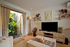 a living room with a television and a table at Sahaja Sawah Resort in Tabanan