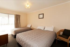 a hotel room with two beds and a chair at Merivale Court Motel & Apartments in Christchurch