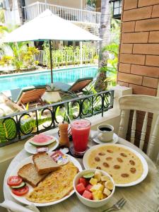 a table with breakfast food on a table in front of a pool at White Coconut Resort in Gili Trawangan