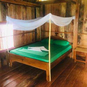 een bed in een houten kamer met een baldakijn bij Robinson Bungalows in Koh Rong Sanloem