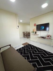 a living room with a couch and a tv on a wall at villa tempoyak homestay in Pantai Cenang