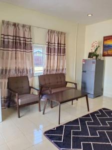 Una sala de estar con un sofá, una mesa y un refrigerador. en villa tempoyak homestay, en Pantai Cenang