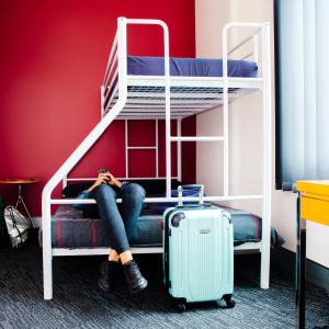 a woman standing next to a blue suitcase on a bed at Wake Up! Sydney Central in Sydney