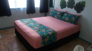 a bedroom with a bed with pink sheets and flowers at Aitutaki Budget Accommodation in Amuri