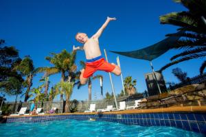 un hombre está saltando a una piscina en Ingenia Holidays Torquay Australia en Torquay