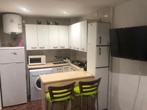 a small kitchen with white cabinets and yellow chairs at Roman Circus views Apartment in Tarragona