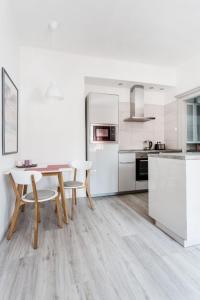 una cocina blanca con mesa y sillas. en Kincsem Budapest Apartman, en Budapest