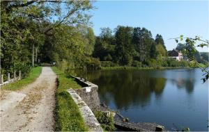 a dirt road next to a river with trees at Le Clos Fleuri in Sautin