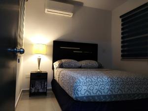 1 dormitorio con 1 cama y 1 lámpara en una mesa en Cerritos Apartamento, en Mazatlán