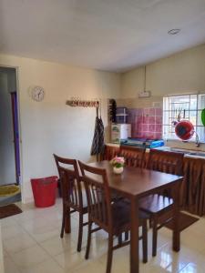 Una cocina con una mesa y sillas de madera. en villa tempoyak homestay, en Pantai Cenang