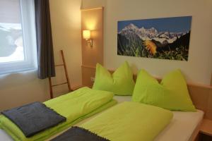 a bedroom with two beds with lime green pillows at Haus Intaba in Ramsau am Dachstein