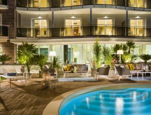 un immeuble d'appartements avec une piscine en face dans l'établissement Grand Hotel Pietra Ligure, à Pietra Ligure