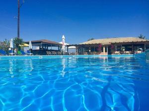 a large swimming pool with a resort in the background at Egrypos Hotel in Petrití