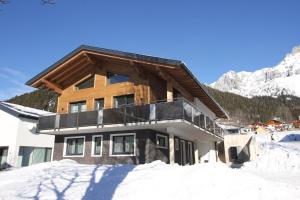 a house in the snow with mountains in the background at Haus Intaba in Ramsau am Dachstein