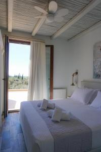 a bedroom with a large bed with a ceiling fan at Anio Residence - Rustic Modern with Sea and Mountain View Terrace in Svoronata