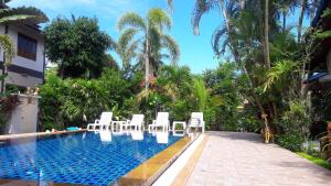 a pool with white chairs and palm trees at Honchana house in Ban Bang Po