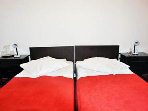 una camera con un letto rosso e bianco con due tavoli di Hotel Central a Călimăneşti