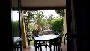 a table and chairs on a patio with a view of a yard at Honey's little house in Palau