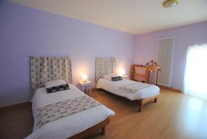 2 Betten in einem Zimmer mit lila Wänden in der Unterkunft La Janenquelle in Sarry
