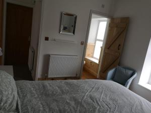 a bedroom with a bed and a chair and a window at Pen-y-Patch in Prestatyn