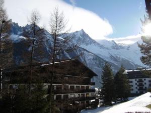 a building in the snow with a mountain in the background at Studio Les Drus / Studio du Brévent in Chamonix-Mont-Blanc