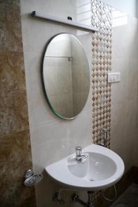 a bathroom with a white sink and a mirror at Hotel Jothi in Coimbatore