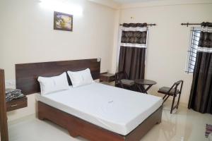 a bedroom with a bed and a table and chairs at Hotel Jothi in Coimbatore