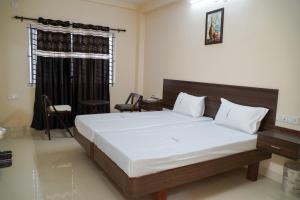 a bedroom with a large bed and a window at Hotel Jothi in Coimbatore