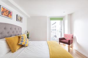 a white bedroom with a bed and a chair at Cosy Apartment in Quiet City-Centre with Car Park in Glasgow