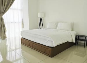 um quarto com uma cama com lençóis brancos e um candeeiro em KSL Hotel & Resort em Johor Bahru