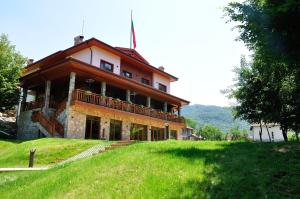 Chalet Balkan في Valevtsi: منزل كبير على تلة مع حقل أخضر